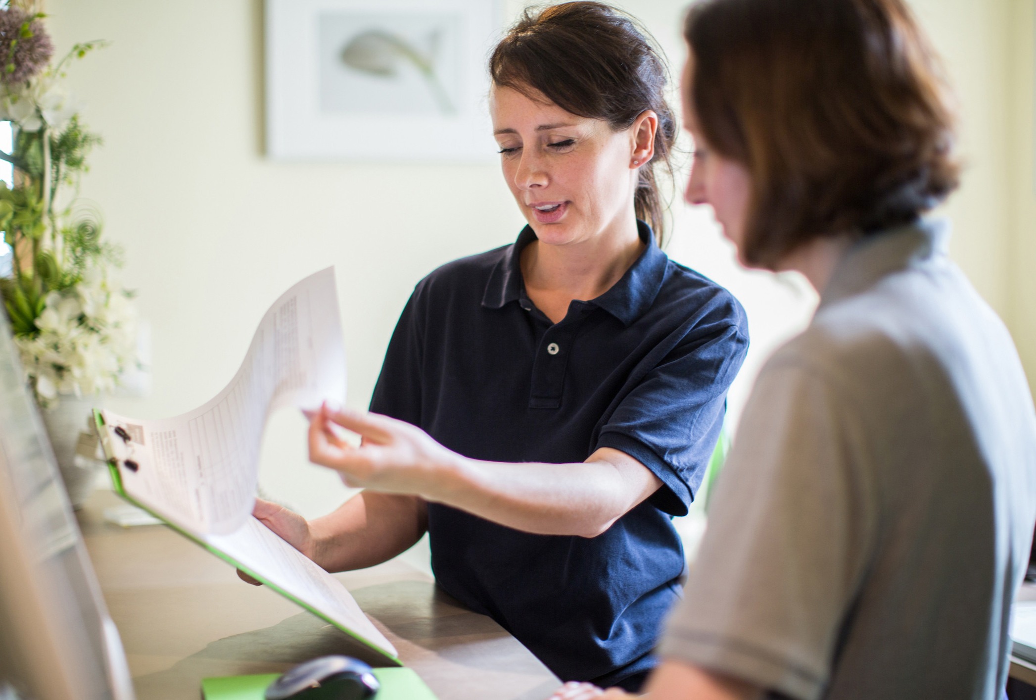 Kvinna visar information på papper till en annan kvinna.